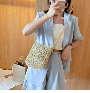 Detail of hand-woven straw crossbody bag with textured circular pattern and thin strap