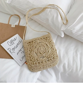 Close-up of straw woven crossbody bag with hollow floral pattern and knit texture