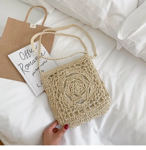 Detailed macro view of the handmade crochet rose pattern on this ivory straw crossbody bag