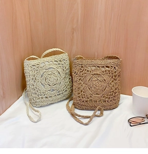 Detail of straw crossbody bags with intricate crochet flower patterns in cream and khaki