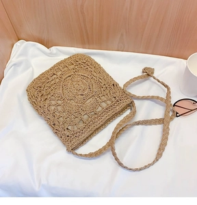 Detailed close-up of handmade woven straw crossbody bag with floral sun pattern design