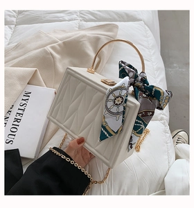 Detail of cream quilted box bag with gold handle and nautical print silk scarf