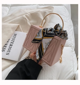 Pink box bag with rhombus texture, gold handle with silk scarf, and chain strap detail
