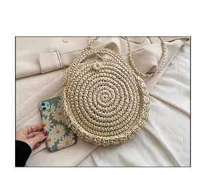 Detail of round straw crossbody bag showing intricate weave and woven shoulder strap