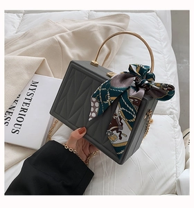 Detail of dark grey quilted box bag with gold handle and vintage silk scarf