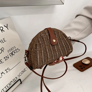 Handwoven semi-circle straw beach bag with brown leather strap and metal buckle detail