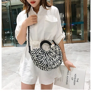 Detail of black and white woven crescent bag featuring rounded handles and braided strap