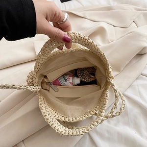 Close-up showing internal capacity and fabric lining of straw woven shoulder bag