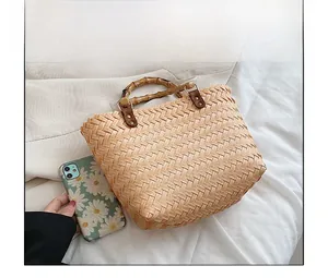 Straw bag detail showing bamboo handle and spacious interior with a phone case for size comparison