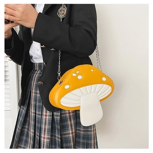 Close-up of a yellow mushroom-shaped crossbody bag with silver chain on a model