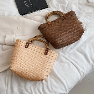 Detailed close-up of woven straw bags featuring natural bamboo handles and brass metal buckles