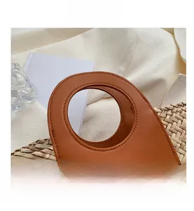 Detail view of the circular leather handle and woven straw texture on a bucket bag