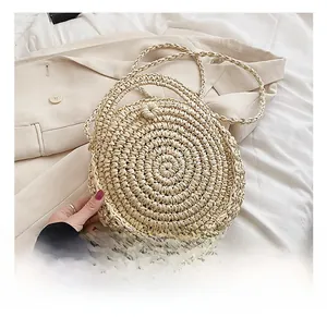 Detailed view of handmade circular straw bag with woven handle and slim shoulder strap