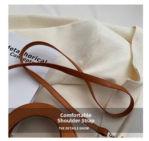 Detail of a brown leather shoulder strap with neat stitching and silver metal hook
