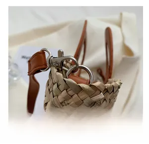 Detail of high-quality silver metal hardware and brown leather strap on a woven bucket bag