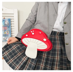 Detail of mushroom crossbody bag with red dotted cap and silver chain strap on a model