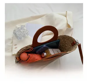 Detail view of woven straw bucket bag with brown leather handles and spacious interior