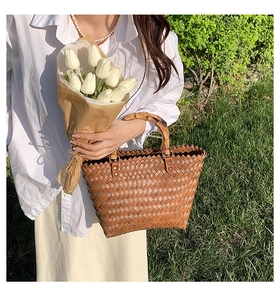 Detailed view of handmade straw woven bag with natural bamboo handles and serrated edge