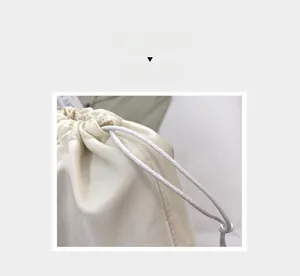Dettaglio della borsa a coulisse color crema con chiusura a cordoncino intrecciato