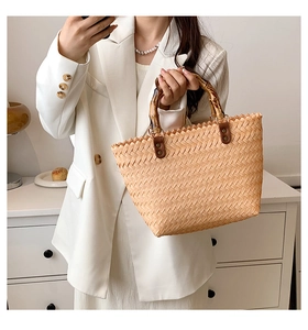Detailed view of handmade woven straw bag with natural bamboo handle and leather accents