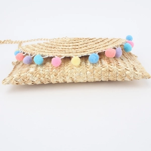 Handmade beige straw crossbody bag with colorful pom-poms and gold chain strap