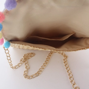 Handmade straw woven crossbody bag with colorful pom-poms and gold chain strap