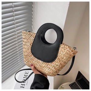 Detail of straw woven bucket bag with black leather handle and shoulder strap