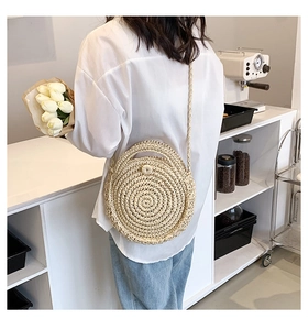 Detail of a round woven straw bag with spiral pattern and dual handles for beach vacation