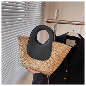 Detail of hand-woven straw bucket bag featuring a contrasting black leather round handle