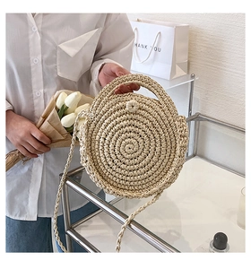 Detail of round straw bag with spiral texture, top handles, and tulip bouquet