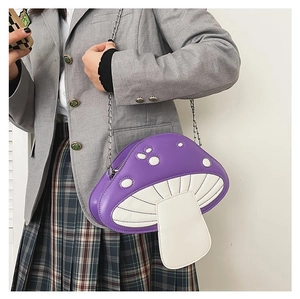 Detail view of a purple mushroom chain bag with white dots worn over a grey blazer