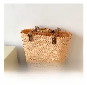 Detailed view of bamboo handle and leather connectors on woven straw tote bag