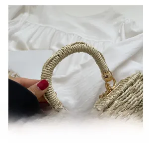 Detail of woven straw bag with circular handle and golden rotary lock on white background