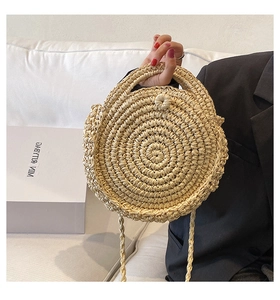 Detail of handwoven beige straw round bag with handle and adjustable shoulder strap