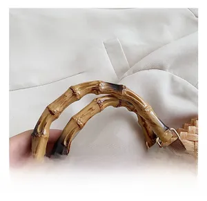 Close-up of natural bamboo handle with gold hardware on a straw woven handbag