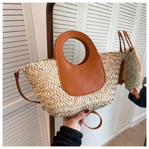 Detail view of woven straw bucket bag with brown leather handles and adjustable strap