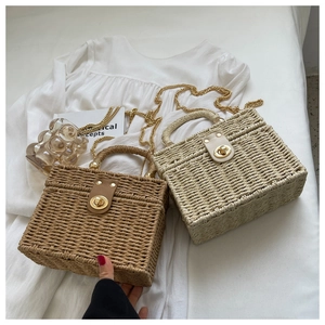Detail view of woven straw box bags in brown and beige with golden chain straps