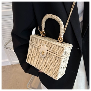Detail of cream woven straw box bag with gold twist-lock and elegant chain strap
