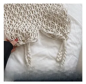 Close-up of a woven cream beach tote bag featuring durable handles and a hollow mesh design
