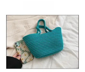 Detailed texture of hand-woven cotton rope bag in teal with phone for scale