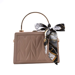 Beige quilted handbag with golden ring handle and elegant decorative silk scarf