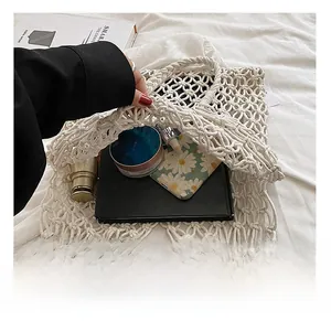 Detail of hand-woven white mesh beach bag showing internal storage capacity with daily items