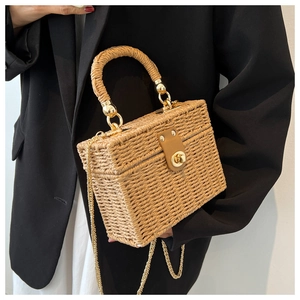 Macro detail of hand-woven straw box bag with natural texture and golden chain strap