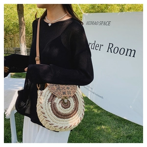 Detail of round straw crossbody bag with ethnic print flap and brown leather strap