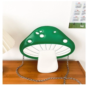 Detail of mushroom cross-body bag with green leather, white spots, and silver chain strap