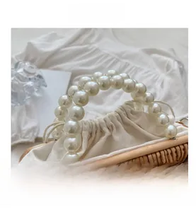 Detail of woven straw bag showing pearl handle and cream canvas drawstring closure