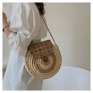 Detail of round straw crossbody bag featuring vintage floral flap and metal lock