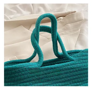 Detail of turquoise woven handbag featuring thick braided handles and premium texture