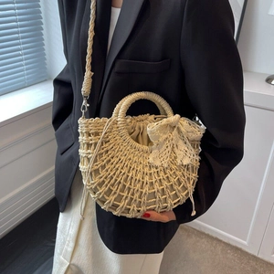 Dettaglio della borsa in paglia intrecciata beige con fiocco in pizzo e fodera