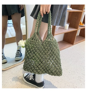 Detail of dark green hand-woven hollow mesh beach bag with braided rope handle